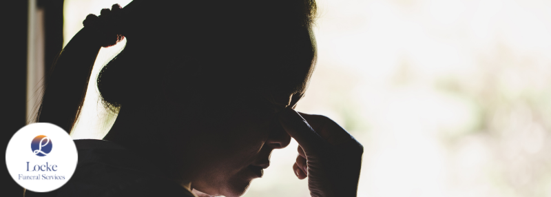 Dark silhouette of a woman pinching her eyes in grief