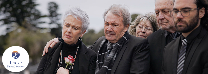 Group of older people dressed in black mourning outside