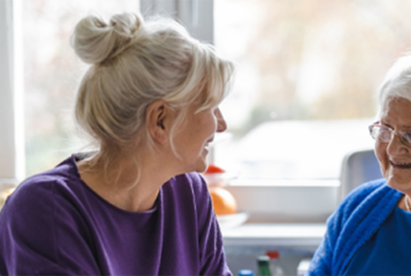 Image shows an older and younger woman talking in their home