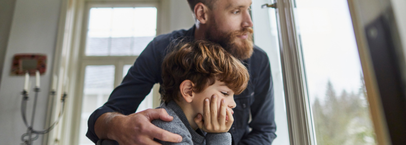 Serious father and son looking out of window